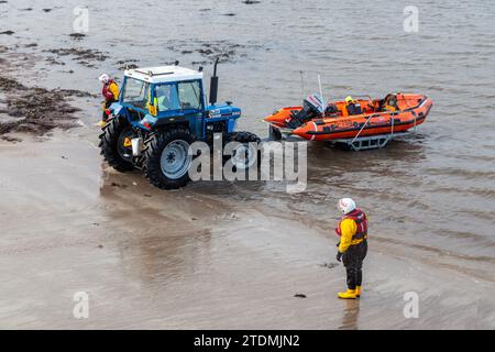 RNLI D class lifeboat on a trailer being pulled out of the sea by a tractor. Stock Photo