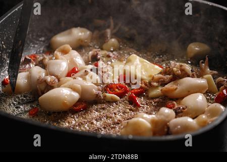 Cooking fresh squid  with chilli pepper, garlic and butter on grill pan, closeup Stock Photo
