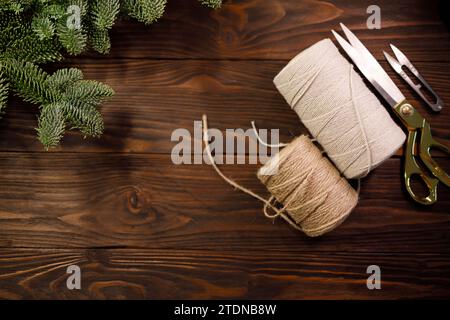 scissors, twisted cotton rope and burlap cord on wooden table decorated with spruce branches Stock Photo