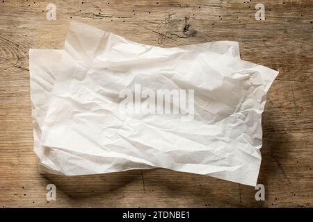 white baking paper sheets on old wooden kitchen table, top view Stock Photo