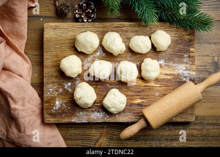 dough balls and rolling pin on wooden cutting board for Christmas baking, top view Stock Photo