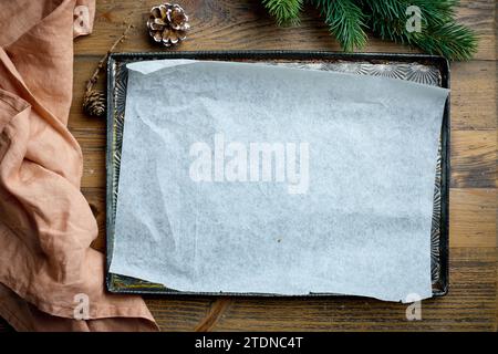 empty baking pan with paper sheet on wooden kitchen table, top view. Christmas baking background Stock Photo