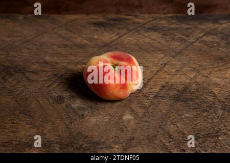 Ripe chinese flat peach fruit or saturn peach on vintage wooden background. Stock Photo