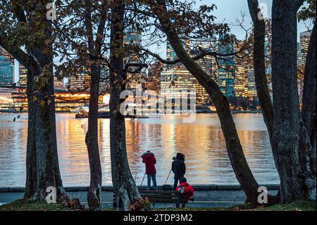 Group of photographer taking a photo with cityscape of illuminated building from Stanley Park in the evening at Vancouver, Canada Stock Photo