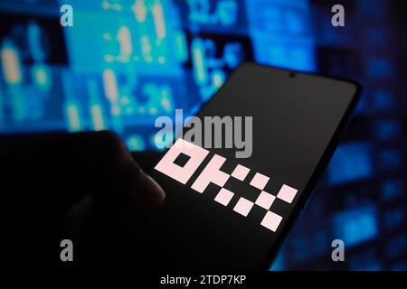 In this photo illustration, the OKX logo is displayed on a smartphone screen with stock market percentages in the background. Stock Photo