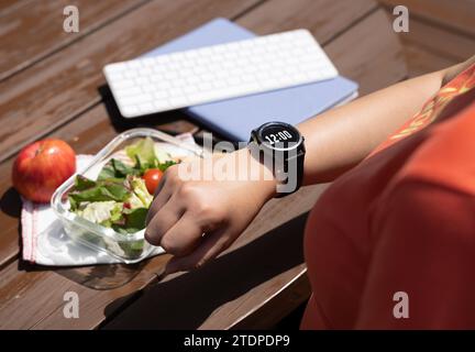A female office worker checks the lunch time and tries to start eating Stock Photo