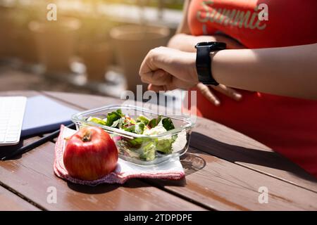 A female office worker checks the lunch time and tries to start eating Stock Photo