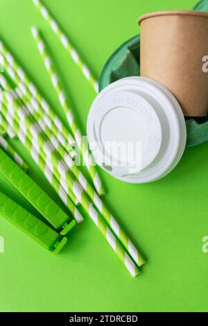 This image features a disposable coffee cup with a white lid, green striped straws, and a bright green background Stock Photo