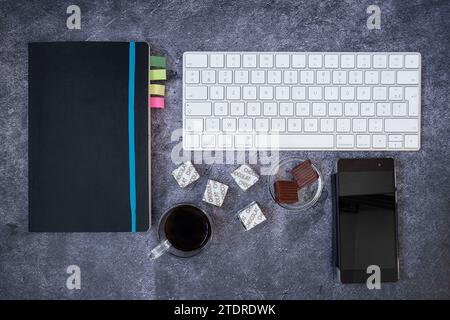 Coffee break with caramels and chocolates on a computer at the office or for leisure. "Chocolate" is written in French on the little squares of confec Stock Photo