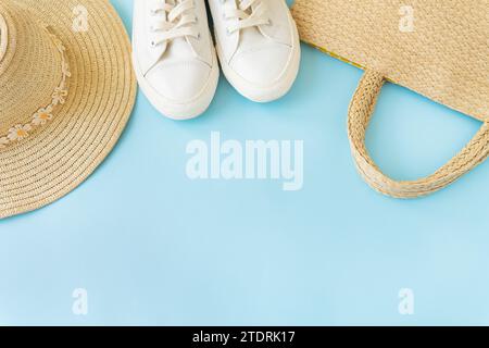 This look features summery pieces on a blue background: white sneakers, a straw hat, and a woven bag. Items are arranged aesthetically, with space for Stock Photo