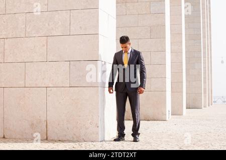 Sad businessman next to some wall looking down Stock Photo