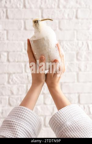 Hands with liquid soap on white brick background Stock Photo