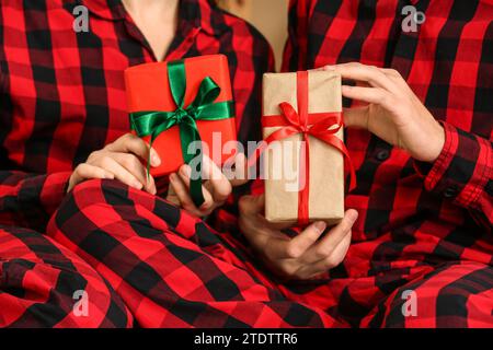 Young couple wearing plaid pajamas with gifts, closeup Stock Photo
