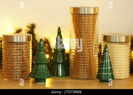 Jars of cereals with decorative Christmas trees on table in kitchen Stock Photo