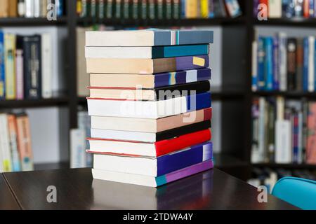 A stack of different books in a large library selected by the reader lies on table Stock Photo