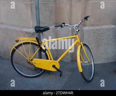Yellow bicycle tied to the pole to prevent theft Stock Photo