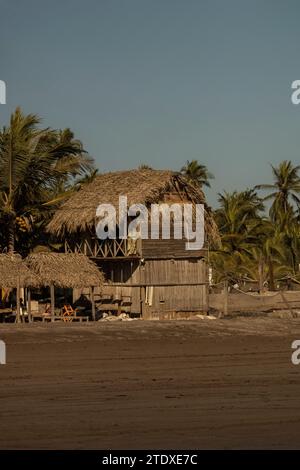 Tropical tranquility: A traditional Pacific Mexican palapa, crafted from wood and woven palm leaves, rises above the sandy shores. Stock Photo