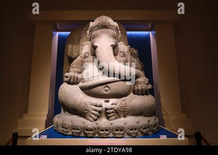 A beautiful, large, fat, cheery, fun stone carved sitting Ganesh elephant god statue. Inside a gallery at the Maha Surasinghanat Building at the Natio Stock Photo