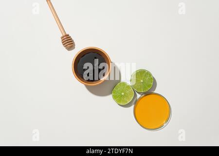 Wooden bowl and petri dish hold honey, accompanied by fresh lemon and honey drizzle on a white background. Embracing natural ingredients in a healthca Stock Photo