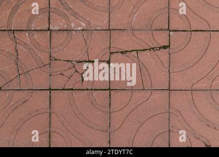 Broken&weathered red square paving stones or blocks with geometric shapes outdoors, viewed from above. High resolution full frame textured background. Stock Photo