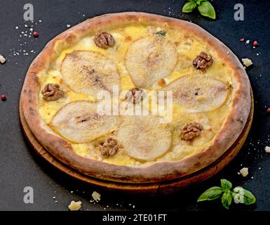 pizza with nuts and pear on a black background. Delicious pizza with pears, gorgonzola cheese, walnuts Stock Photo