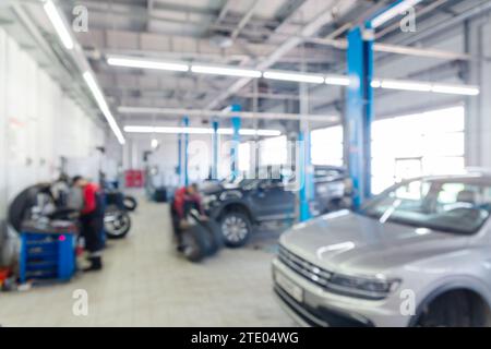 Blurred image inside tire service center. Replacing rubber on car wheels. Wheel balancing. Car tire service center auto repair workshop blurred backgr Stock Photo