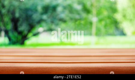 Table and a tree in the meadow in the background. Empty old rustic wooden table and defocused green grass and tree in the background Stock Photo