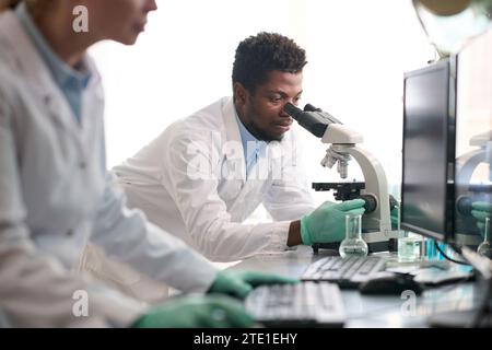 Laboratory Worker Looking through Microscope Stock Photo