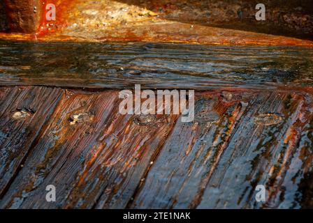 Wet, shiny, cracked and worn floor boards of an old, wooden ship wreck on the Mediterranean coast in Israel. Stock Photo
