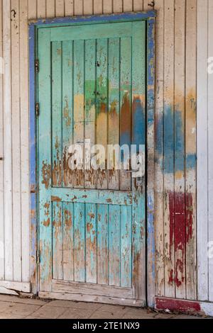 Colorfully painted old door with peeling wooden boards andsilver door handle. Stock Photo
