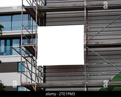 Empty banner on a construction site template. White copy space for a company logo or information of the building. The advertising is at a scaffolding. Stock Photo