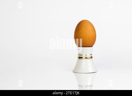 Chicken egg on a stand is peeled on a white background with reflection Stock Photo