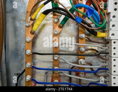 Three-phase copper high-voltage busbar in a metal box with automatic circuit breakers. Stock Photo