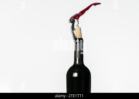 Corkscrew screwed into the cork taken out of a bottle of red wine isolated on a white background Stock Photo