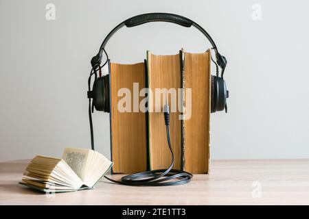 Books with headphones and a mini-jack plug inserted between the pages on a table against a light background. Audiobook concept Stock Photo