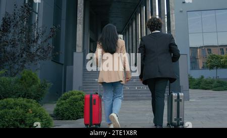 Back view from behind business partners friend colleague executives managers travelers passengers businesswoman businessman with baggage luggage Stock Photo