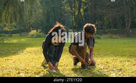 Two people woman man runners sportive girl guy Indian Arabian couple standing in park outdoors forest talking friendly speaking talk tying sneakers Stock Photo
