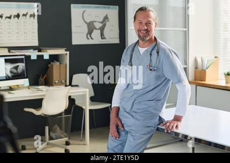 Caucasian vet doctor posing nearby examination table at his office smiling at camera Stock Photo