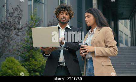 Pensive thoughtful worried serious pensive business partners Arabian businessman Indian businesswoman colleagues managers coworkers discuss laptop Stock Photo