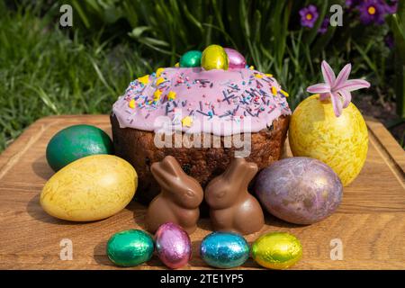 Happy Easter, delicious glazed Easter cake, colored eggs, mini egg candies and chocolate bunnies. Stock Photo