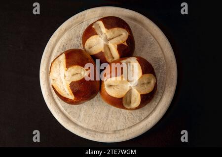 German Pretzel Rolls on Wood Plate on Black Background Stock Photo