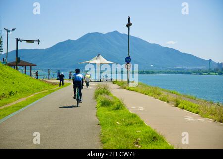 Namyangju City, South Korea - September 30, 2023: Cyclists ride along the Han River bike path, moving away from the camera, with the grand Geomdansan Stock Photo