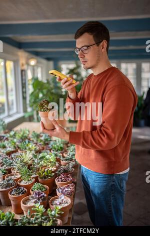 Plant lover checking flower names by making photos, reading information in mobile application  Stock Photo