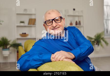 Portrait of a happy, smiling senior man in eyeglasses sitting on the sofa at home Stock Photo