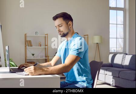 Young man studying from home, using laptop, and taking online courses on Internet Stock Photo