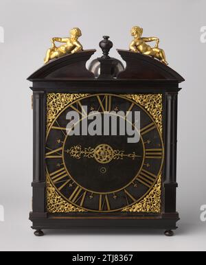 Table clock made of wood; square cupboard on flattened bolpoten, between two Tuscan half -columns, Pieter Visbach (I), 1650 - 1700 Wooden table clock. The timepiece is caught in a small square cupboard on flattened bol feet, between two Tuscan half -columns. The you are filled with openwork rank motifs. The cupboard is crowned with a broken quarter -round fronton, with a vase on a pedestal in the middle. Two children rest on the two parts of the pediment, with the backs towards each other. The timepiece is marked at the rear: "Pieter Visbach Fecit Hagae". According to tradition of Michiel de R Stock Photo