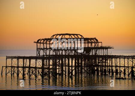 The derelict West Pier at dusk Brighton, England. Built in 1866 and closed in 1975, the pier is still Grade I listed and a well known landmark. Birds flock to the rusting structure. Stock Photo