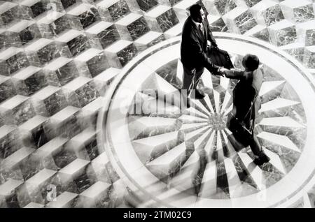 An overhead view of two businessman shaking hands while standing on an ornate marble tile floor Stock Photo