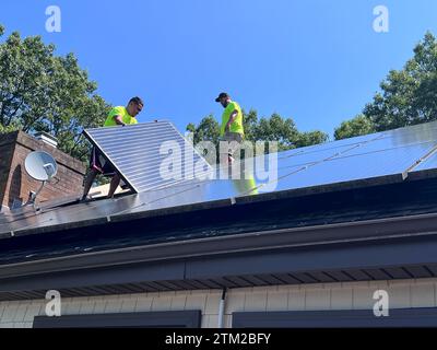 Workman installing solar panels on the roof of a residential homes in New England Stock Photo