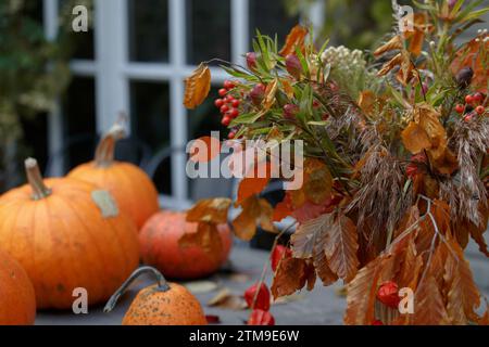 Pumpkins on a wooden table. Halloween decor with various pumpkins, autumn vegetables, with maple leaves and flowers. Autumnal Background.  Harvest and Stock Photo